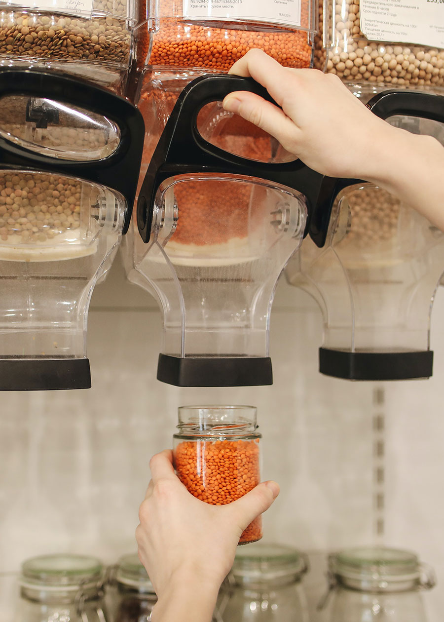 Photo of consumer using a bulk grain dispenser and reusable container.